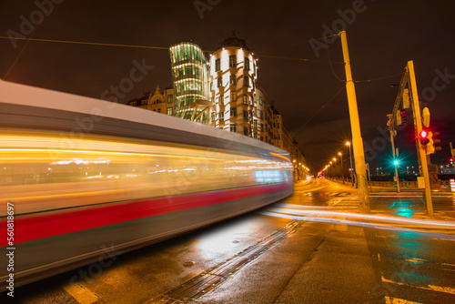 Dancing house or Fred and Ginger building in downtown. Built by Vlado Milunic and Frank Gehry - Long exposure photo of Tram moving on a street  photo