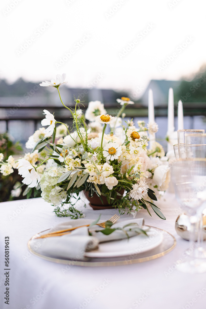 Banquet table decorated with plates, cutlery, candles, glasses and flower arrangements Banquet table decorated with plates, cutlery, candles, glasses and flower arrangements