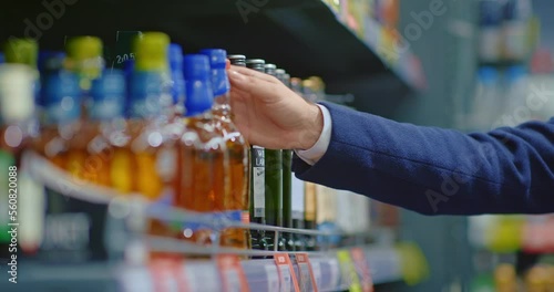 alcohol addicted man taking whisky bottle from shelf in liquor store, closeup of hand, 4K, Prores