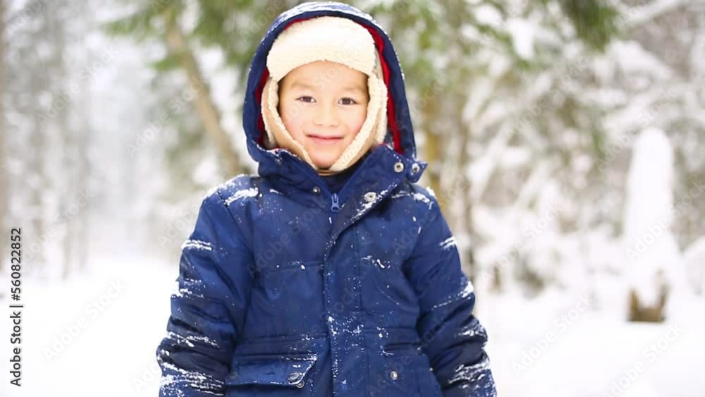 An Asian happy boy is smiling and playing in snowy forest in winter An Asian happy boy is smiling and playing in snowy forest in winter