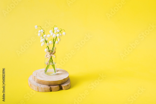 Lilies of the valley bouquet in a miniature jar on a yellow background with copy space. Mothers day blank greeting card