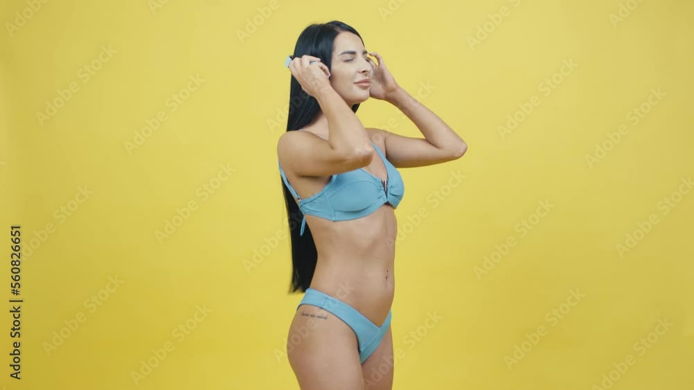 Beautiful young woman in headphones on a yellow background listening to music and dancing Beautiful young woman in headphones on a yellow background listening to music and dancing