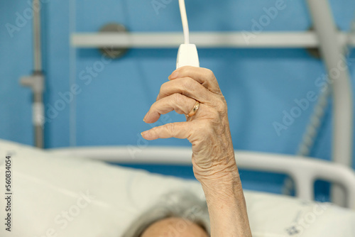 Emergency button in the hospital to call a nurse. Patient woman in a hospital room calling a nurse. The hand of an elderly patient holds the emergency button in the hospital.