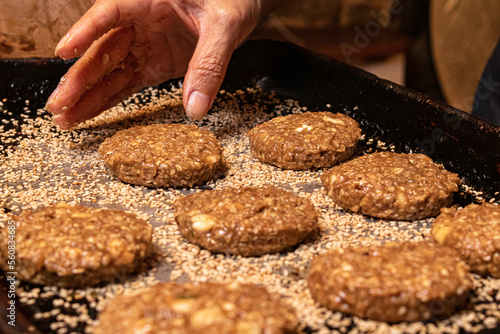 Close-up de mão feminina colocando na assadeira cookies de banana com castanha de caju sendo preparados para o cozimento.  photo