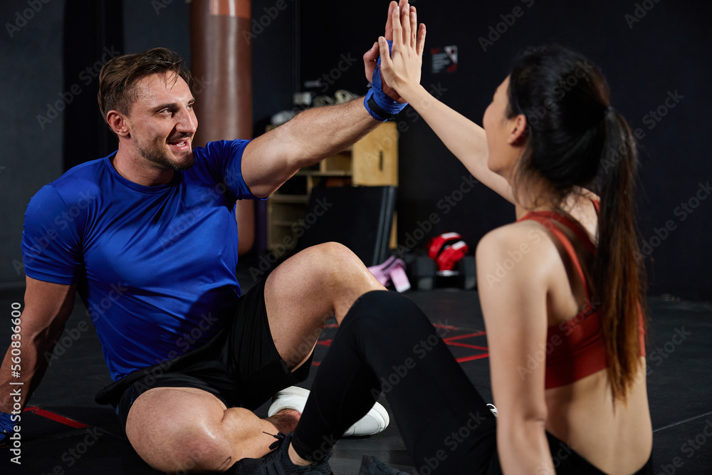 trainers or athletics giving hi five pose after workout in the gym trainers or athletics giving hi five pose after workout in the gym