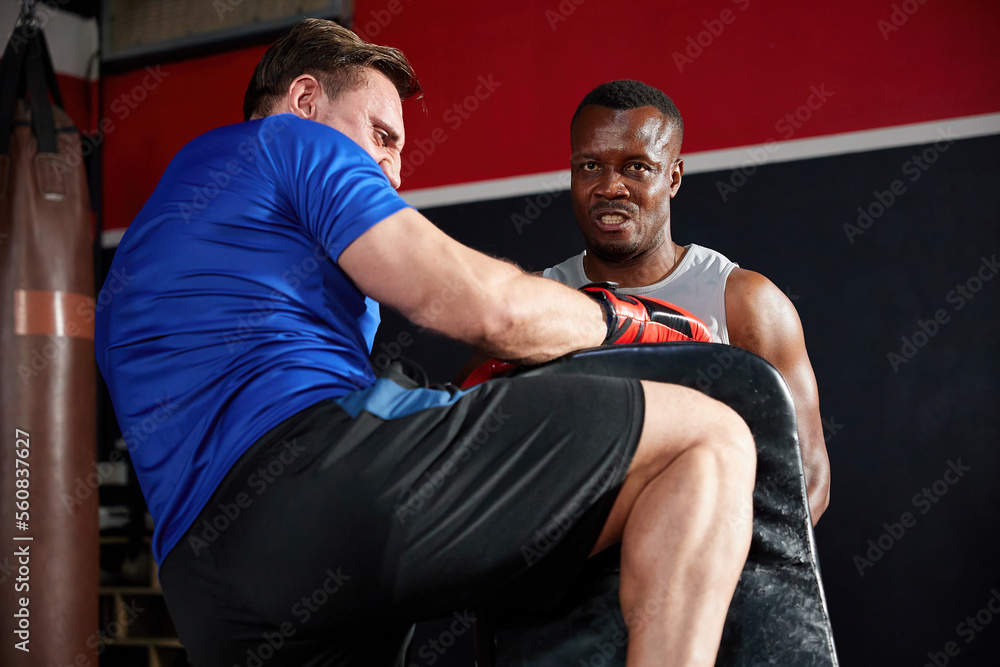 sportsman or fighter training and kickboxing with trainer in the gym sportsman or fighter training and kickboxing with trainer in the gym