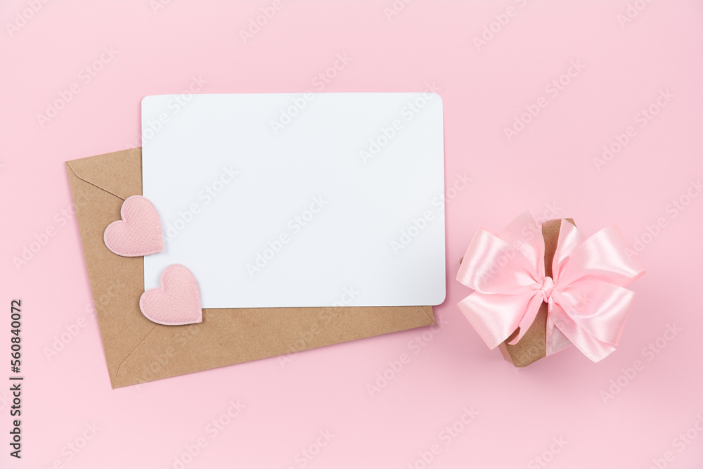 Empty note with envelope, pink hearts and small gift box on pink background Empty note with envelope, pink hearts and small gift box on pink background