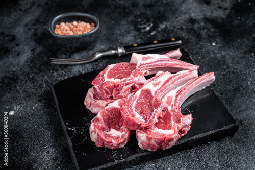 Uncooked lamb mutton chops, raw meat steaks. Black background. Top view