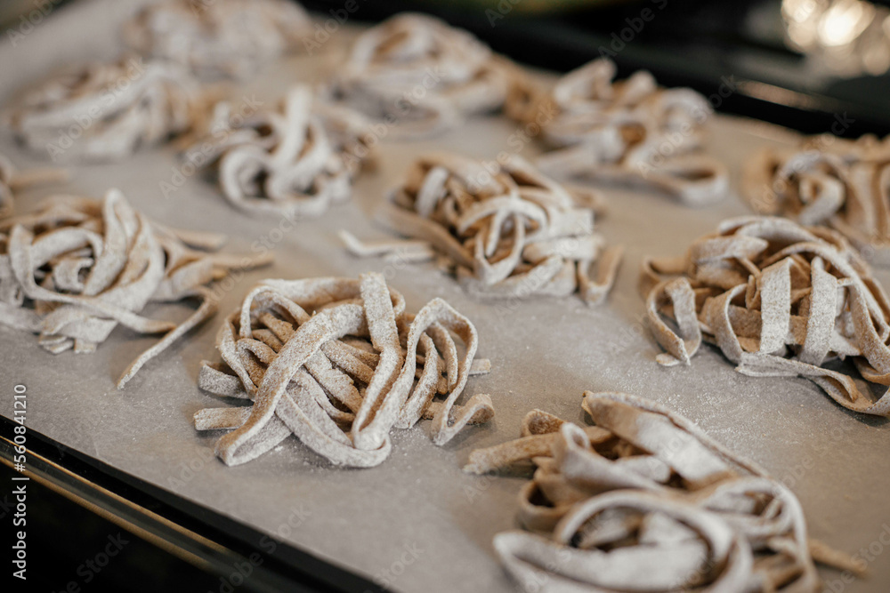 Homemade pasta. Dry fettuccine noodles in nests on baking tray close up. Making whole-grain pasta