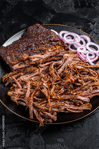 BBQ pulled pork meat on plate. Black background. Top view