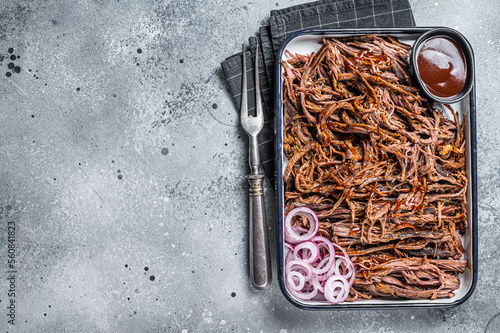 Pulled beef meat with hot chili sauce in baking dish. Gray background. Top view. Copy space