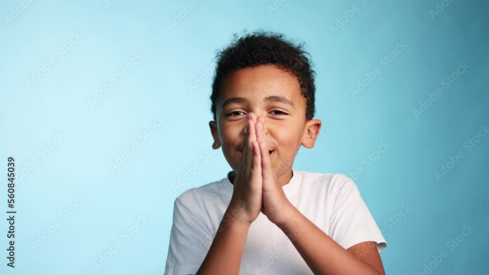 Cute african american little boy holding hands folded begging about something from parents asking please on isolated blue background Cute african american little boy holding hands folded begging about something from parents asking please on isolated blue background