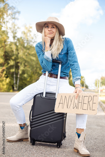 фотографія Grimacing, waiting, independent blond woman in cowgirl hat hitchhike by road wit