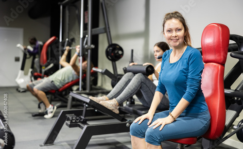 Caucasian woman training on shoulder press machine in gym
