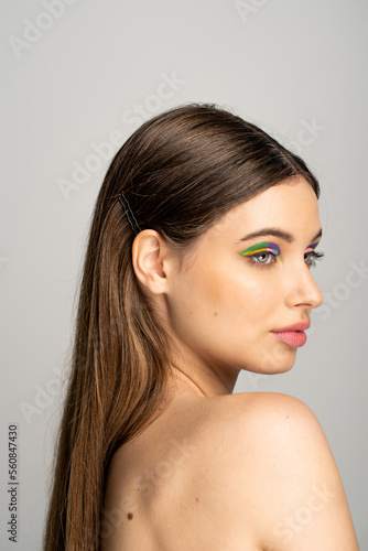 Pretty teenager with naked shoulders and colorful visage isolated on grey.