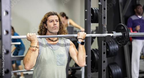 Muscular man doing barbell exercises in the gym