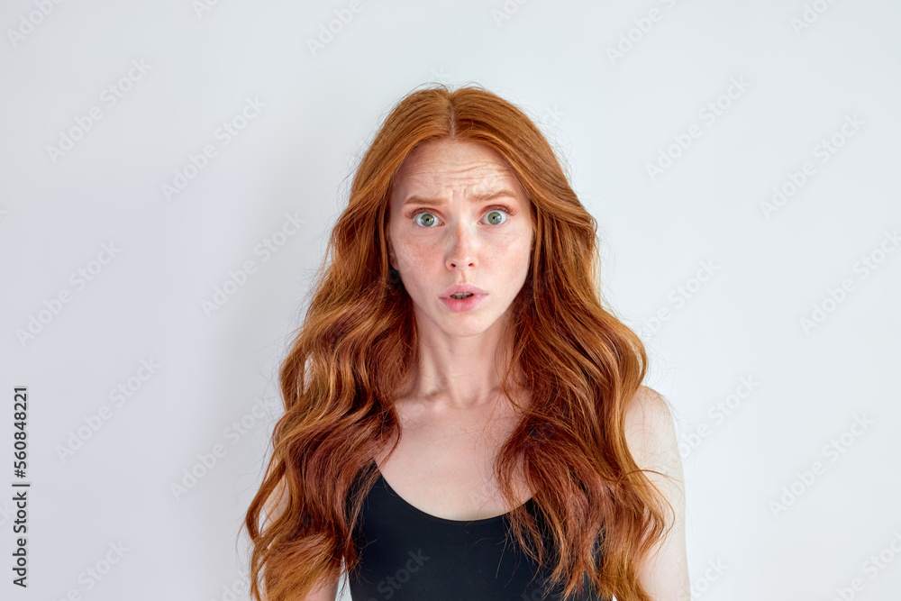 Portrait of pretty, surprised woman with opened mouth and eyes looking at camera isolated on white studio background, copy space for advertisement. human emotions, fear, shock concept