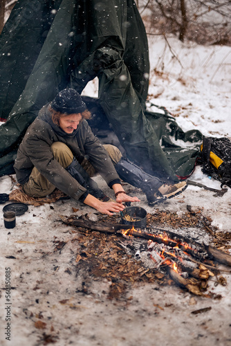 happy Man warming hands on bonfire in nature in cold season, winter. travel lifestyle photo. adventure active vacations outdoor. Extreme camping. in snowy frozen forest alone, calm and pacified