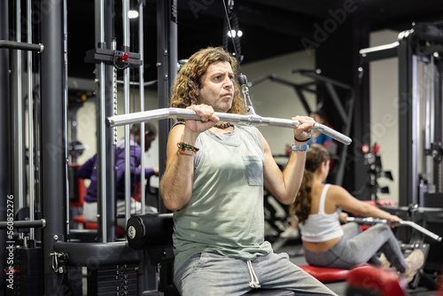Caucasian man training on lat pull down machine in gym