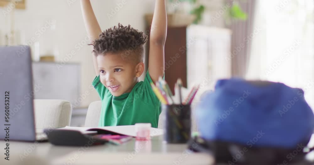 Happy african american boy sitting at table, using laptop for online lesson Happy african american boy sitting at table, using laptop for online lesson