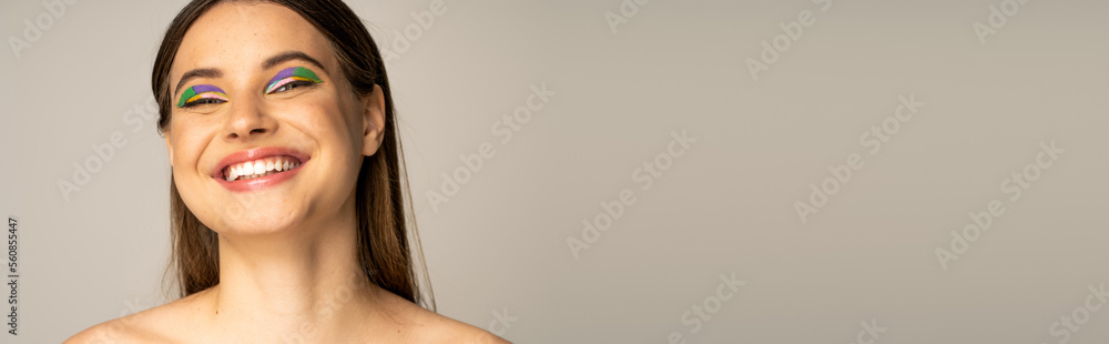 Teen model with colorful visage smiling at camera isolated on grey, banner. Teen model with colorful visage smiling at camera isolated on grey, banner.