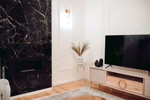 Stylish pastel apartment, Details of luxurious sofa, wooden tv table, golden light fixtures and fireplace wall