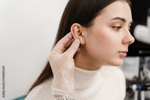 Otoplasty surgical reshaping of pinna and ear. Otoplasty ear surgery. Surgeon doctor examines girl ears before otoplasty cosmetic surgery. photo