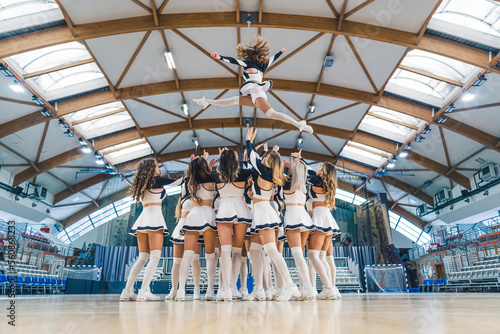 Canvas Print A group of cheerleaders are captured in a dynamic and athletic moment, performing a stunt by lifting one of their team members into the air