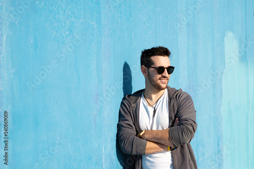 Portrait of young bearded man with sunglasses leaning against wall