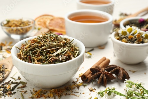 Bowl of dry aromatic tea on white wooden table  space for text