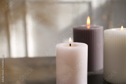 Different burning candles on grey table indoors. Space for text