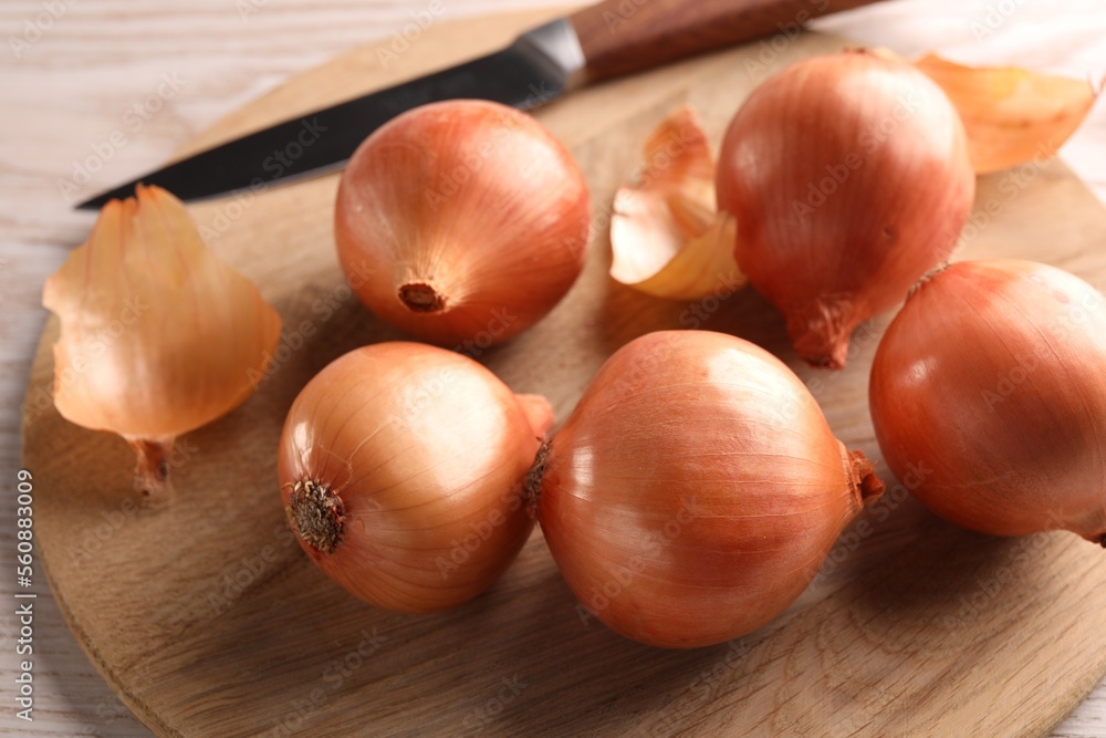 Obraz premium Tray with ripe onions and knife on wooden table, closeup