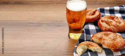 Tasty pretzels and glass of beer on wooden table, space for text. Banner design photo