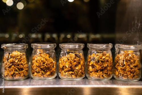 Small portion glass jars of granola stand in a row on the shelf 