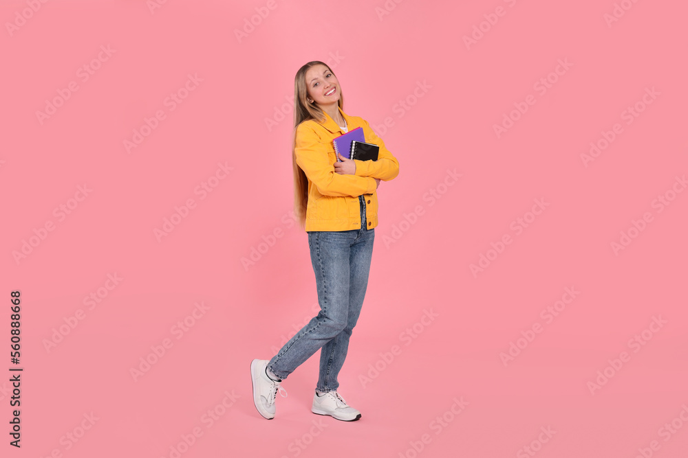 Naklejka premium Teenage girl with notebooks on pink background