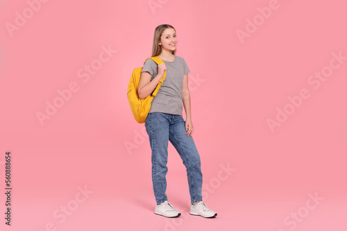 Teenage girl with backpack on pink background