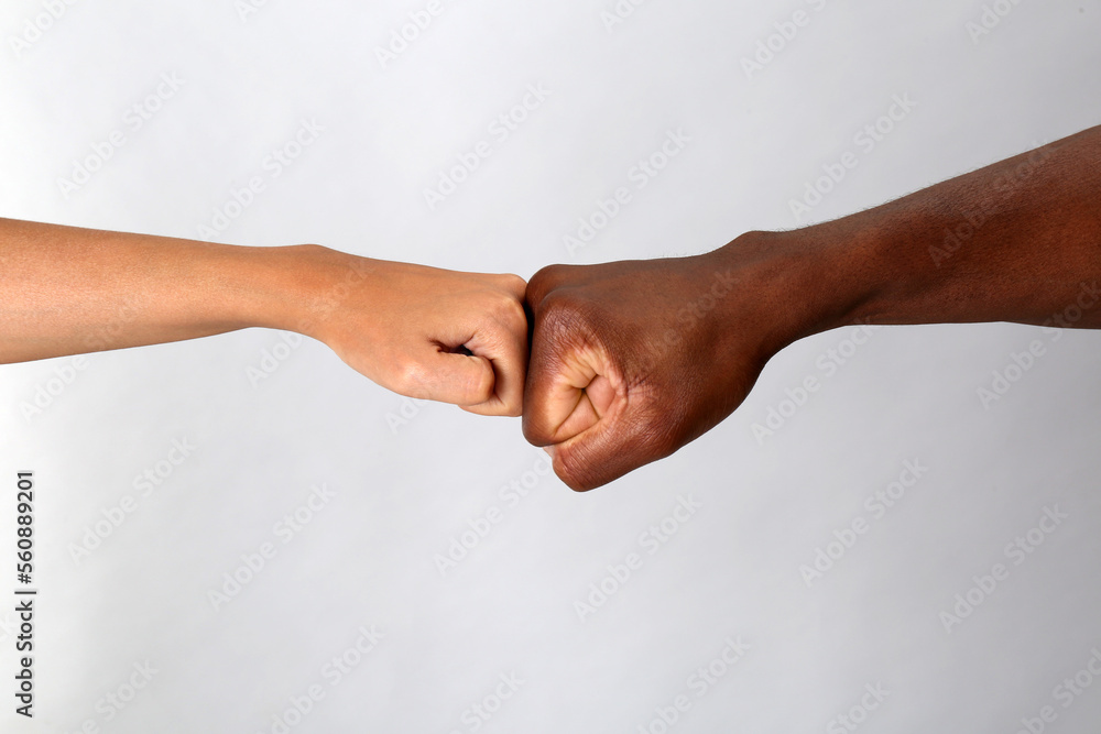Fototapeta premium Woman and African American man making fist bump on light grey background, closeup