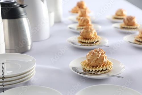 Many delicious waffles with cream served on white table for coffee break