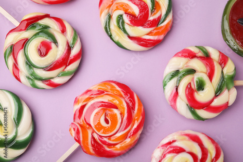 Many colorful lollipops on violet background, flat lay