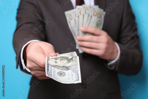 Man holding money on light blue background, closeup. Currency exchange