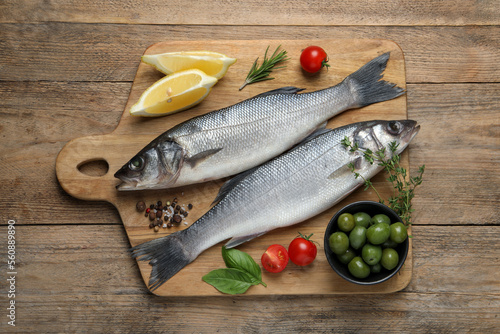 Sea bass fish and ingredients on wooden table, top view