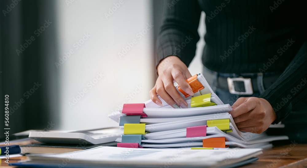 Businesswoman hands working in Stacks of paper files for searching and checking unfinished document achieves on folders papers - obrazy, fototapety, plakaty 