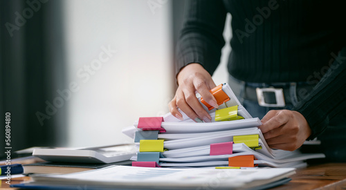 Businesswoman hands working in Stacks of paper files for searching and checking unfinished document achieves on folders papers photo