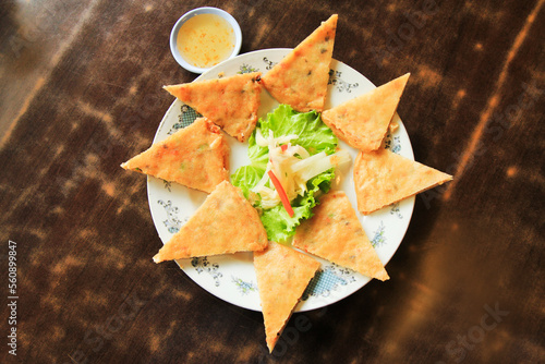 Deep fried vegetable spring roll  cut into triangles whit plum sauce on the wood table, top view 
