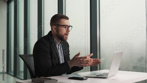 An upset male office worker excuses himself over a laptop video call