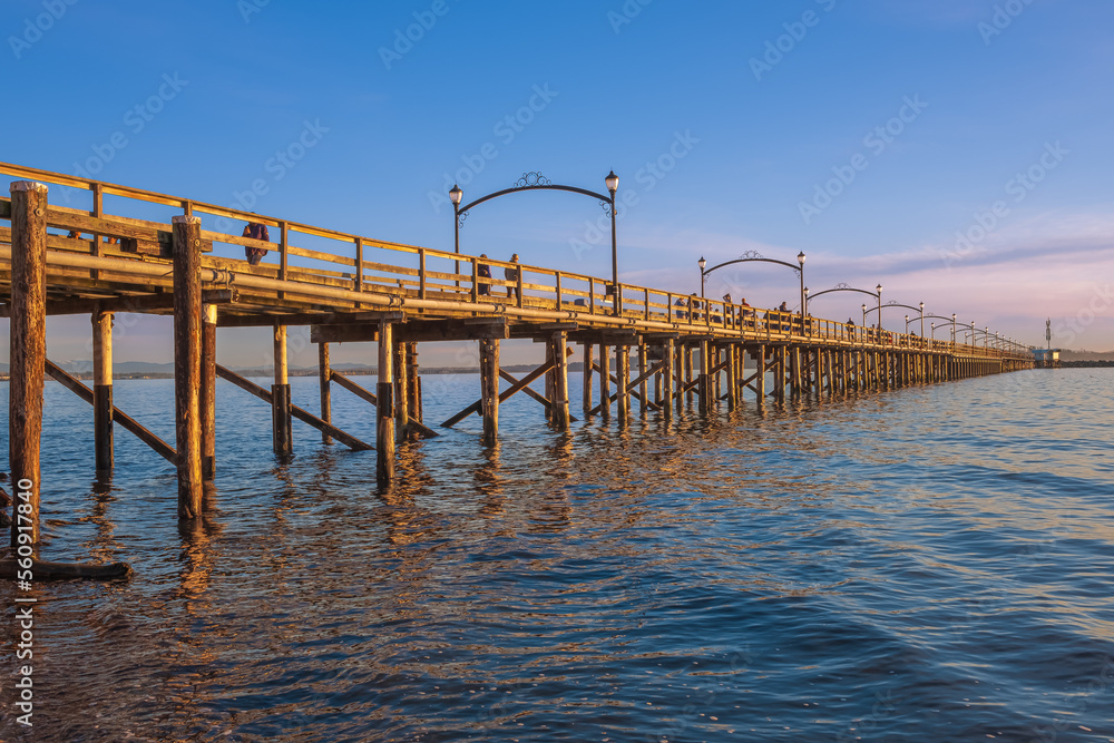 Naklejka premium Pier on the sea at sunset. View of a wooden bridge Twilight. Colorful sunset over the White Rock Pier British Columbia.