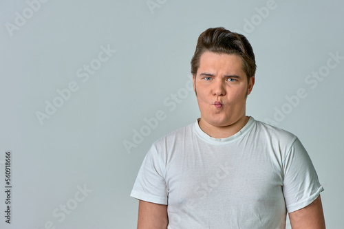 a man puffing out his cheeks with a funny face on a gray background, emotions © Евгений Порохин