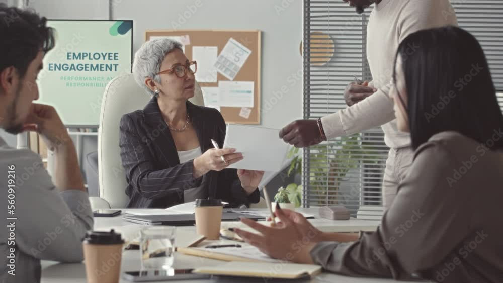 Successful adult businesswoman of Asian ethnicity conducting meeting with team in her office, discussing company results of the year Successful adult businesswoman of Asian ethnicity conducting meeting with team in her office, discussing company results of the year