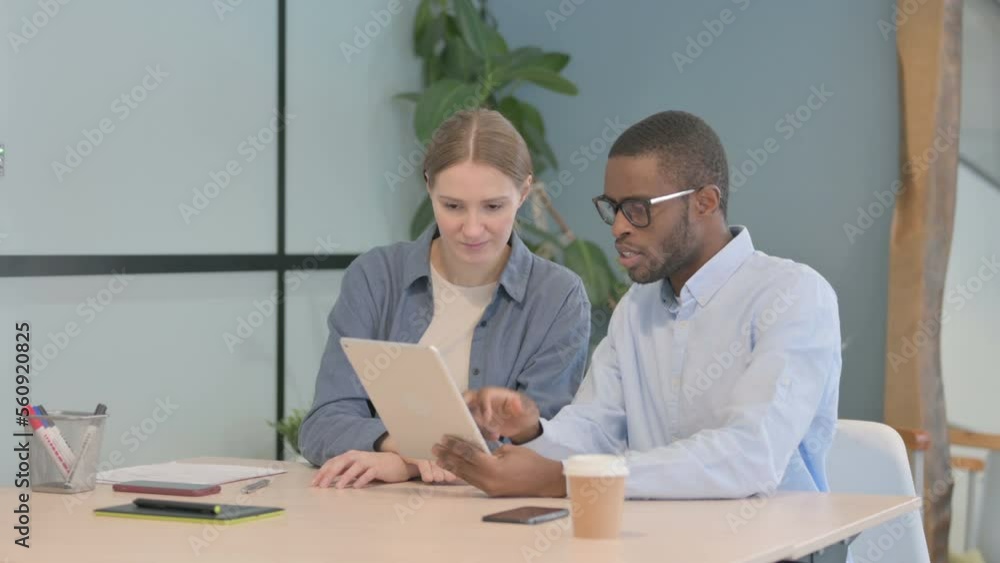 Young Business People Discussing Work on Tablet in Office Young Business People Discussing Work on Tablet in Office