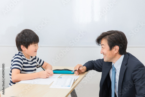 小学生に勉強を教える笑顔の塾講師・先生（日本人男性） 